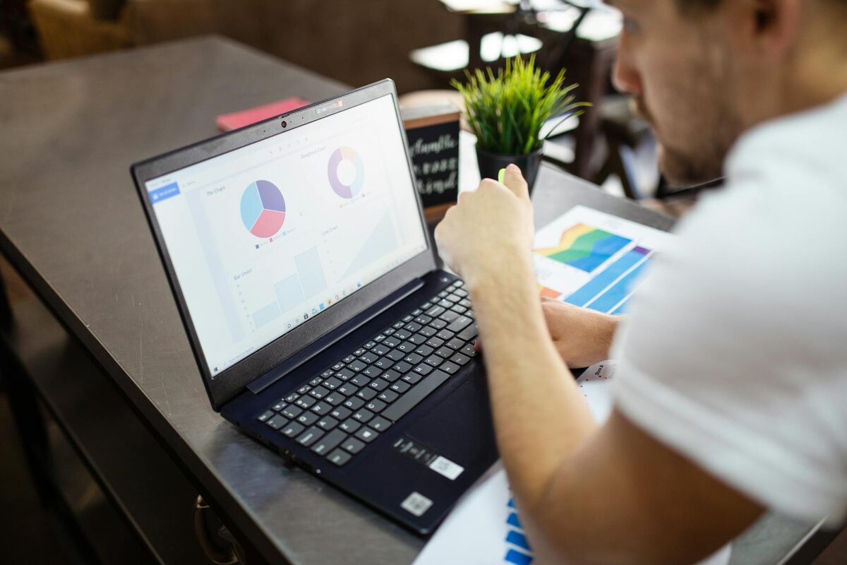 Person reviewing business charts and graphs on a laptop — content analytics dashboard overwhelm vs. solo creator metric focus