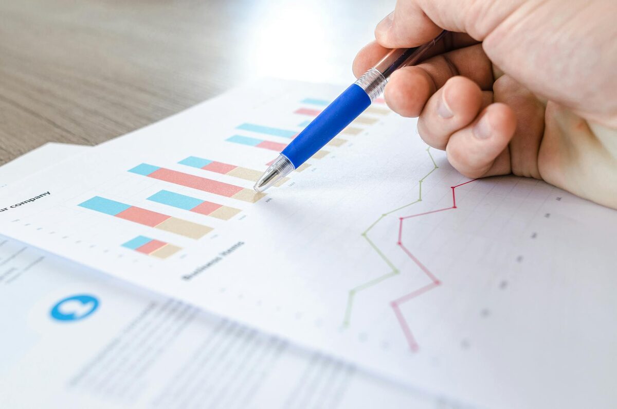 Hand analyzing colorful bar charts and survey data on paper — solo creator CTR comparison by content format