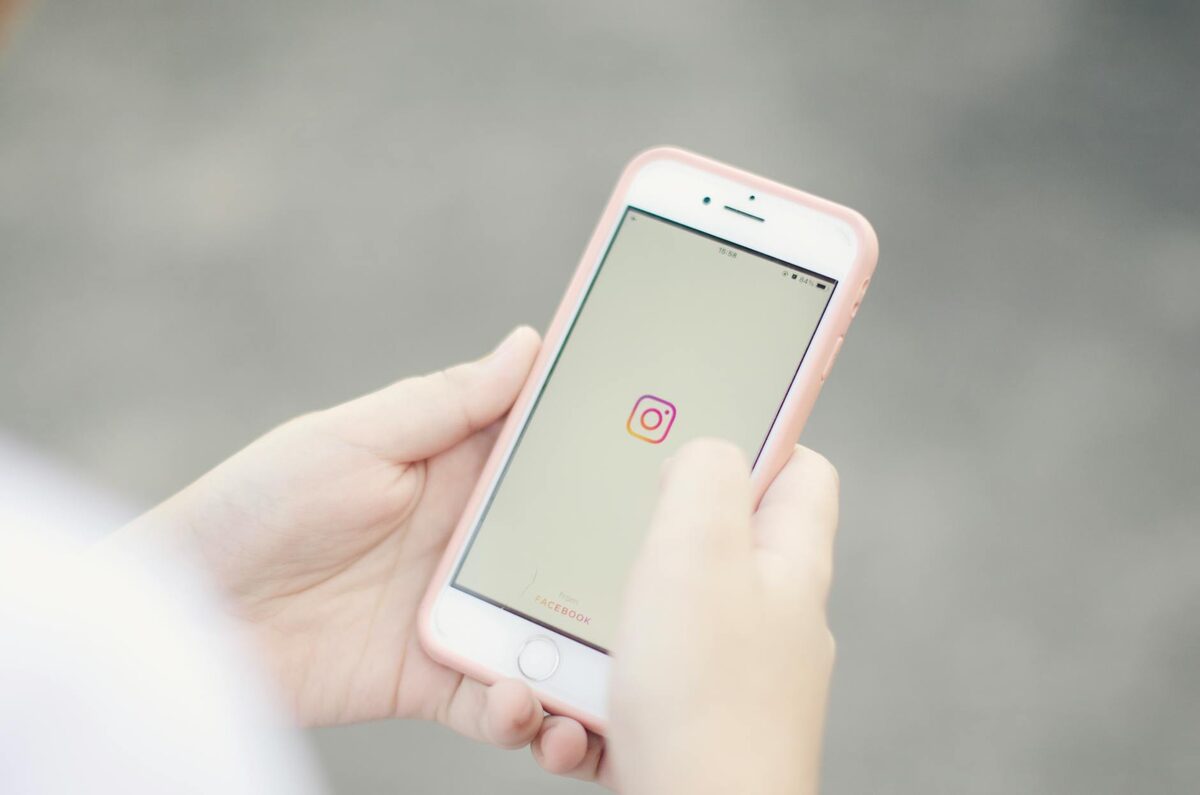 Hands holding a smartphone with the Instagram app open, representing the variety of Instagram Story ideas for solo creators