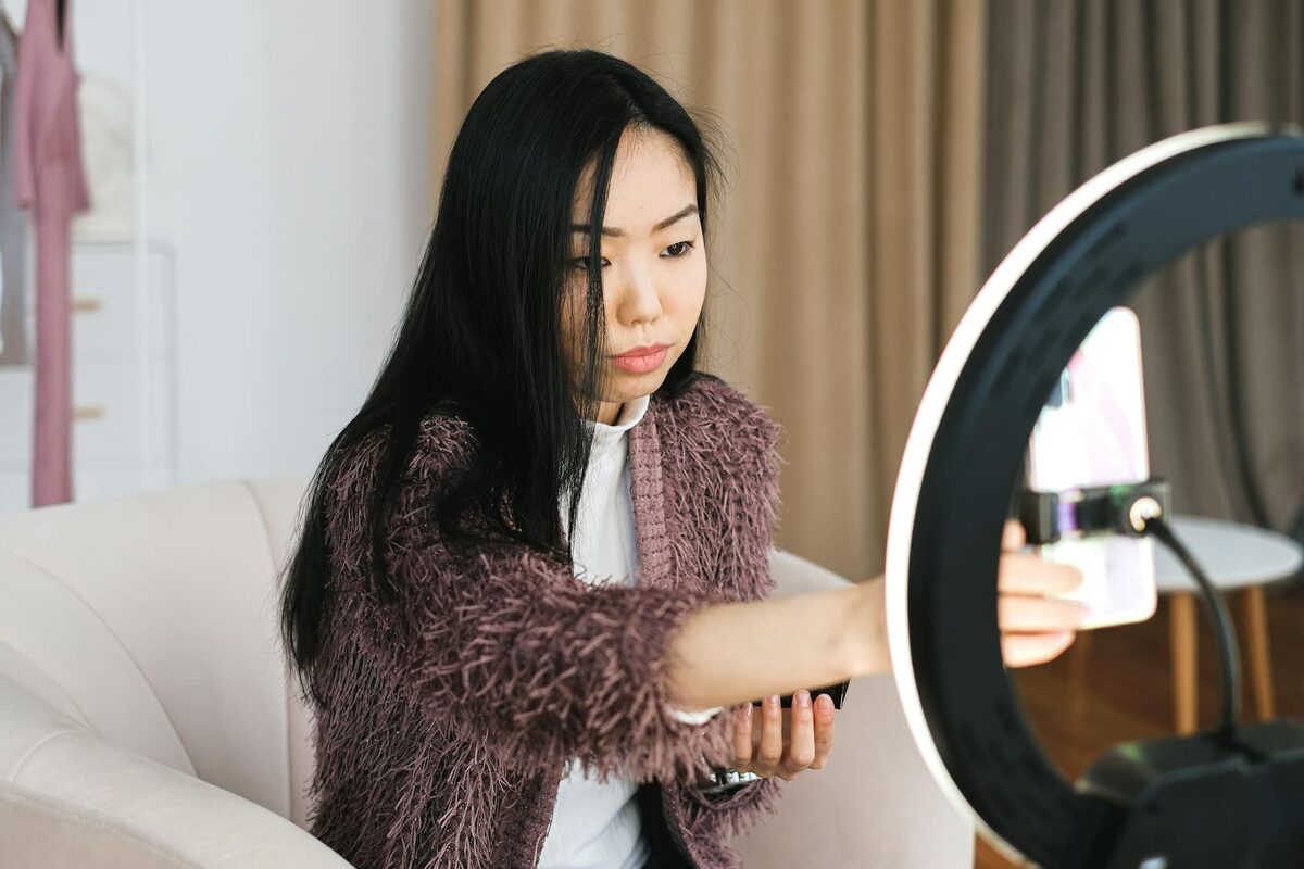 Woman filming with a smartphone and ring light at home — a solo creator setup for Instagram Story sales sequences
