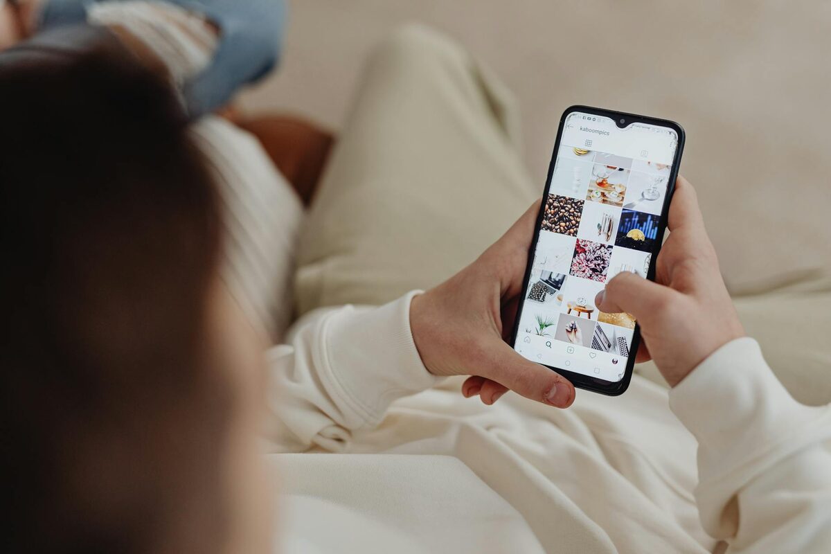 Person browsing Instagram on a smartphone, illustrating the challenge of deciding what to post on Instagram for business