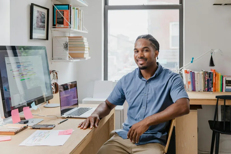 Professional smiling at desk in a modern office, representing the approachable presence that drives LinkedIn engagement