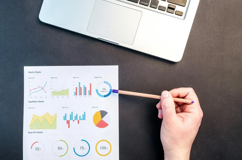 Person reviewing data charts and analytics results on paper with a laptop nearby
