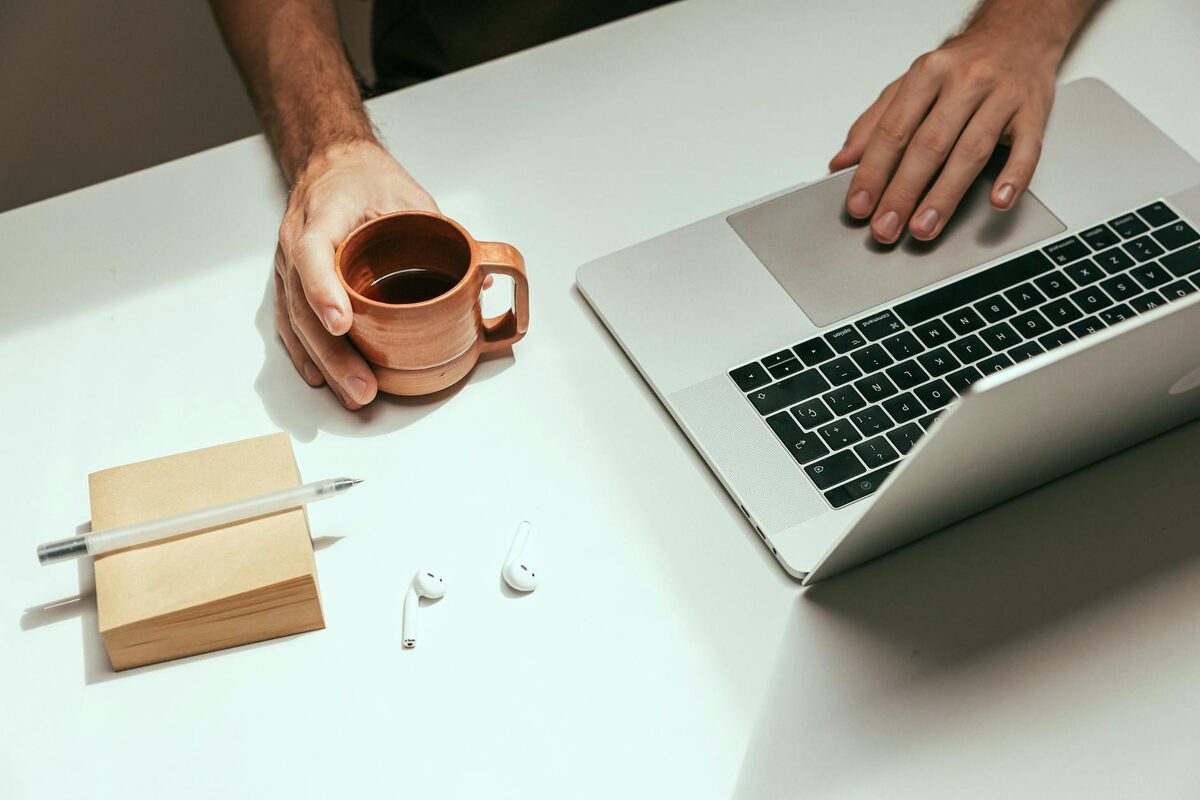 Solo creator working at a laptop with coffee nearby, building a LinkedIn content strategy from a home workspace