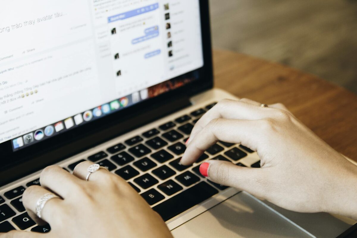 Person typing on a laptop with a social media interface open, representing the blank-page challenge of LinkedIn post ideas