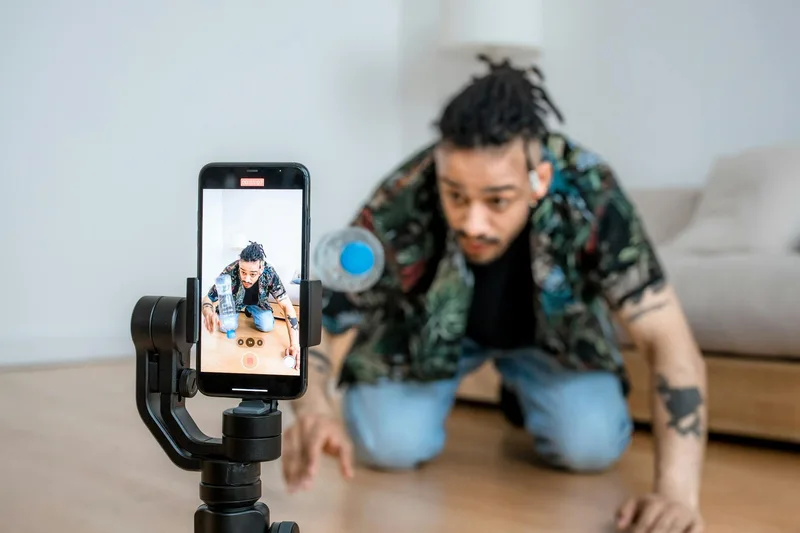 Man filming himself with a smartphone on a gimbal indoors — TikTok batch production workflow for solo creators