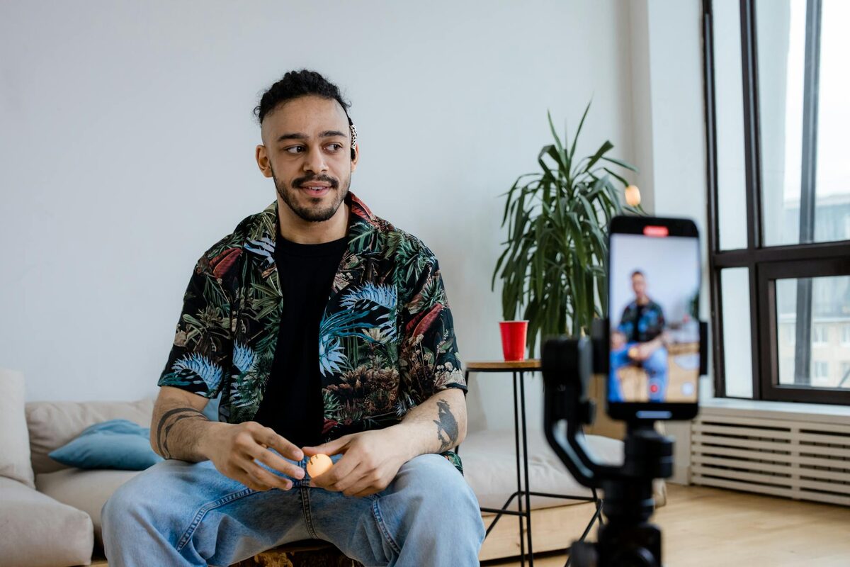 Young man creating a TikTok video with a smartphone and tripod indoors, showing a high-completion-rate content setup