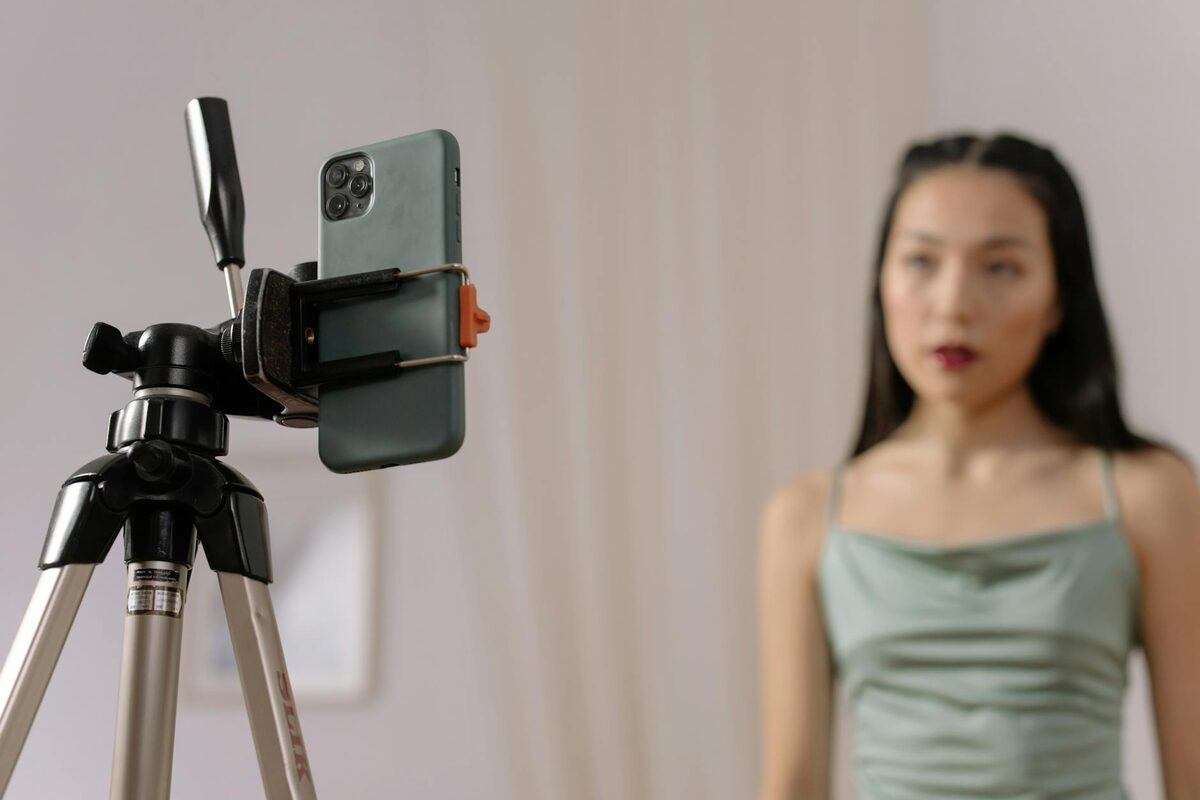 Woman recording video on a smartphone on a tripod indoors — a TikTok sales content idea for solo creators
